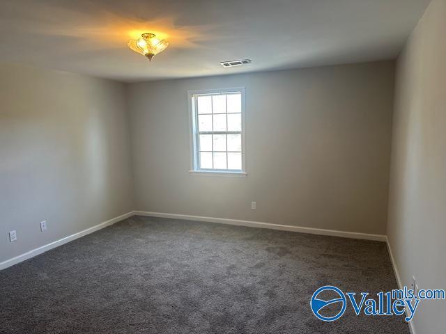 spare room featuring dark colored carpet