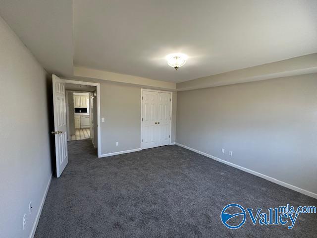 unfurnished bedroom with dark colored carpet