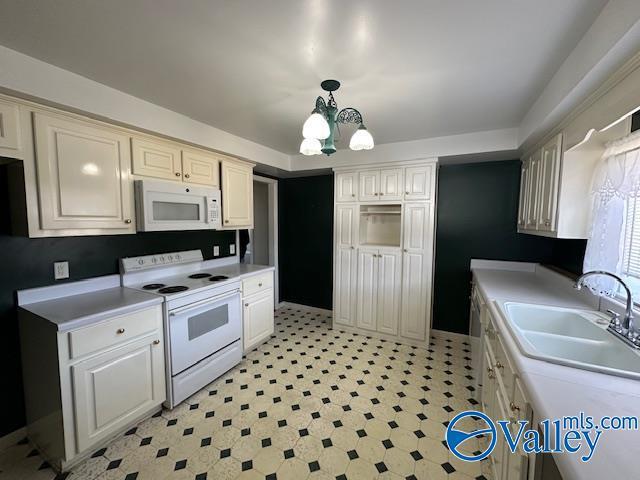 kitchen with pendant lighting, white appliances, an inviting chandelier, and sink