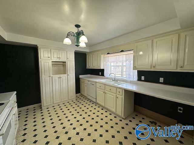 kitchen featuring dishwasher, sink, a chandelier, hanging light fixtures, and a tray ceiling