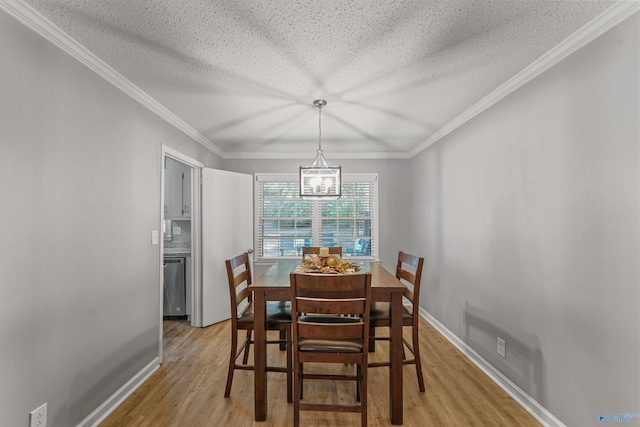 dining space featuring light wood-style floors, a textured ceiling, baseboards, and crown molding