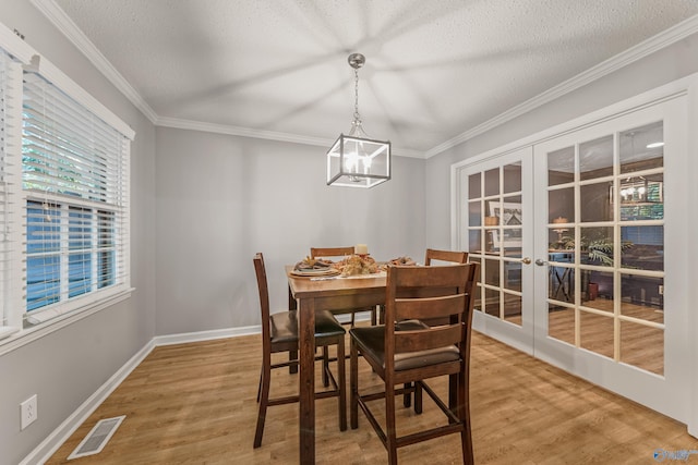 dining area with light wood-style floors, french doors, visible vents, and ornamental molding