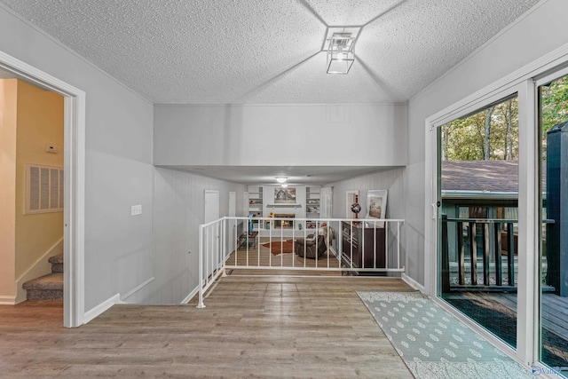 interior space with baseboards, a textured ceiling, visible vents, and wood finished floors