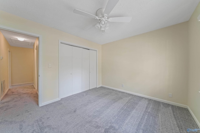 unfurnished bedroom with carpet floors, attic access, a closet, and a textured ceiling