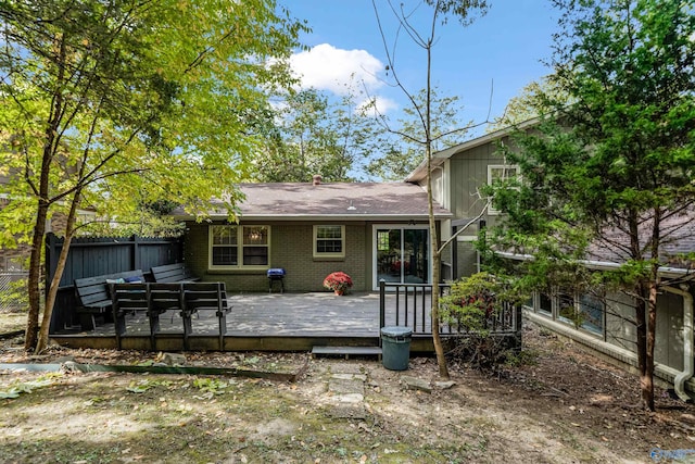 rear view of house featuring fence, a deck, and brick siding