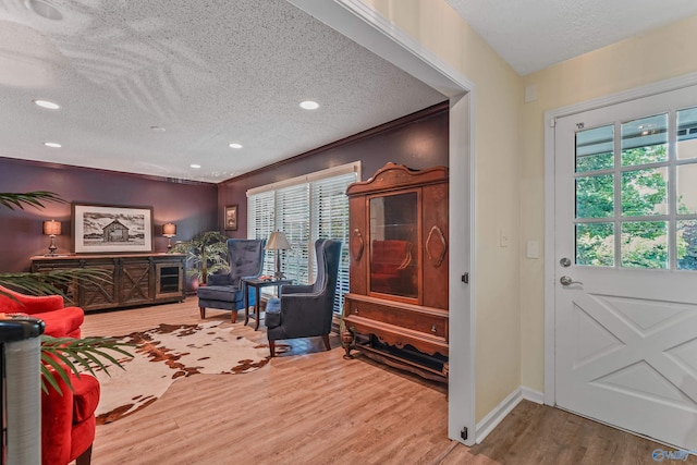 living area with recessed lighting, a textured ceiling, baseboards, and wood finished floors