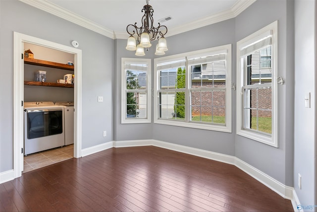 unfurnished dining area featuring washing machine and clothes dryer, ornamental molding, hardwood / wood-style floors, and a notable chandelier