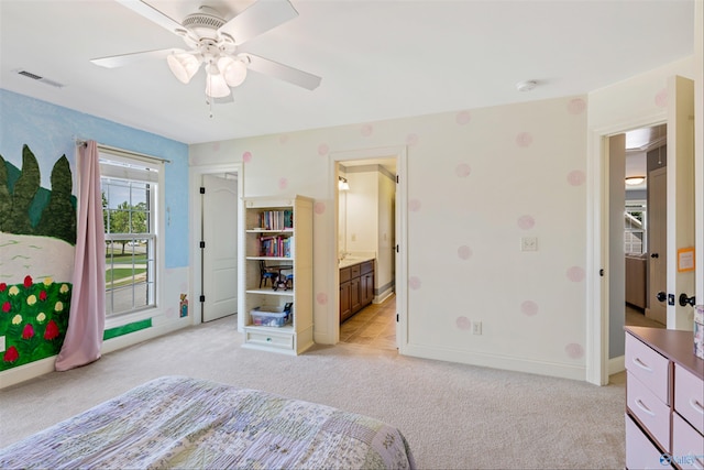 bedroom featuring ceiling fan, connected bathroom, and light carpet