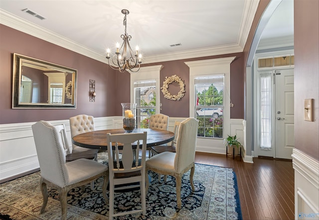 dining space with crown molding, dark hardwood / wood-style floors, and an inviting chandelier