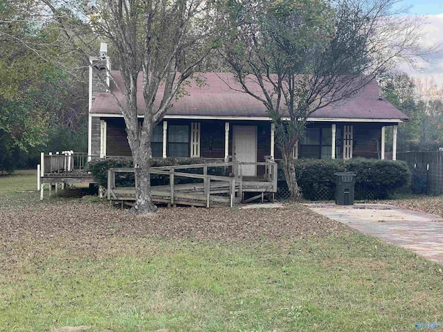 ranch-style home with covered porch, a chimney, and a front lawn