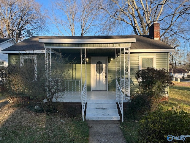 bungalow-style house with covered porch and a chimney