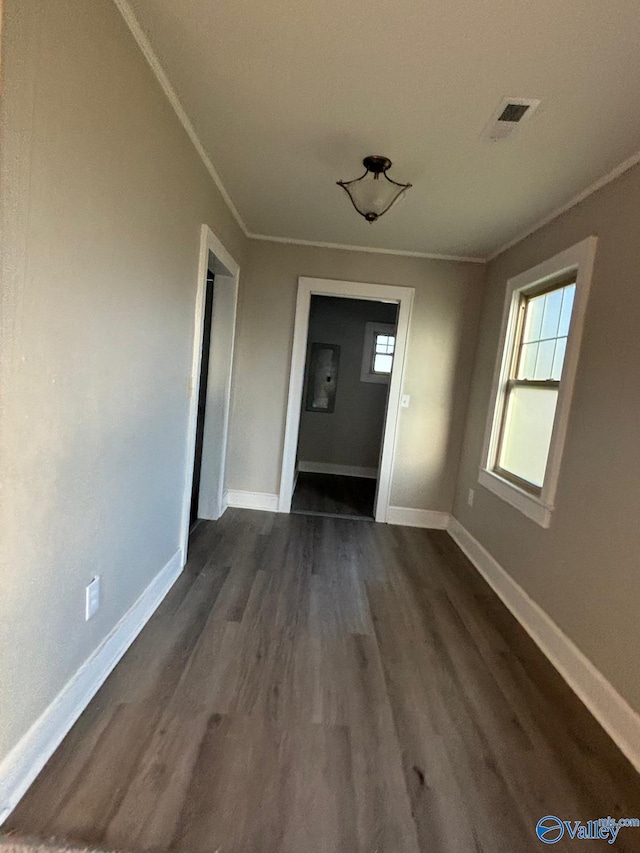 interior space featuring dark wood-style floors, baseboards, visible vents, and crown molding