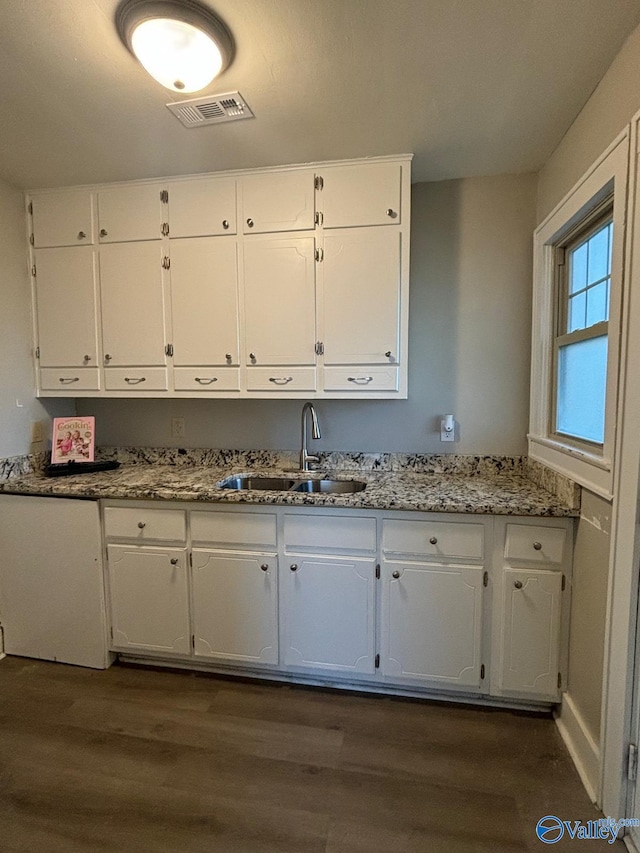 kitchen with visible vents, dark wood-type flooring, white cabinetry, a sink, and light stone countertops