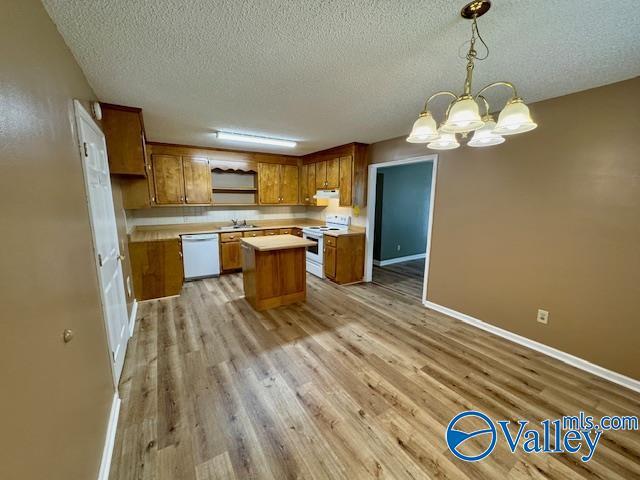 kitchen featuring sink, white appliances, light hardwood / wood-style floors, and a center island