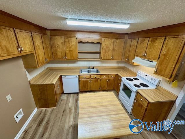 kitchen with sink, white appliances, a textured ceiling, and light wood-type flooring