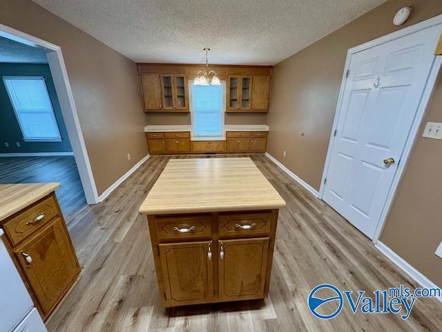 kitchen featuring a notable chandelier, decorative light fixtures, a textured ceiling, and light wood-type flooring