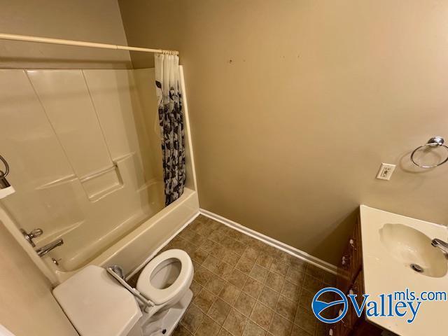 full bathroom featuring shower / bath combination with curtain, toilet, and sink