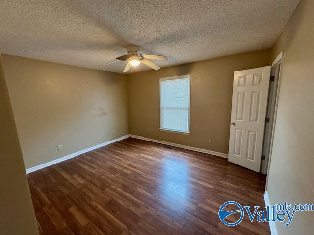 unfurnished room with dark hardwood / wood-style flooring, a textured ceiling, and ceiling fan