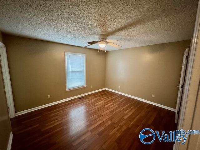 unfurnished bedroom featuring ceiling fan, dark wood-type flooring, and a textured ceiling