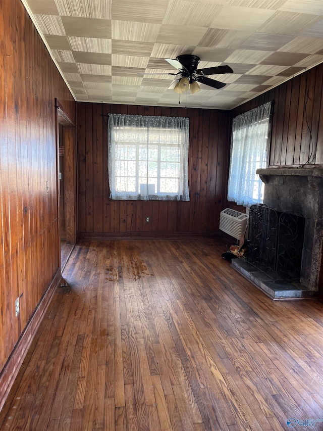 unfurnished living room with a wealth of natural light, a wall mounted air conditioner, and hardwood / wood-style floors