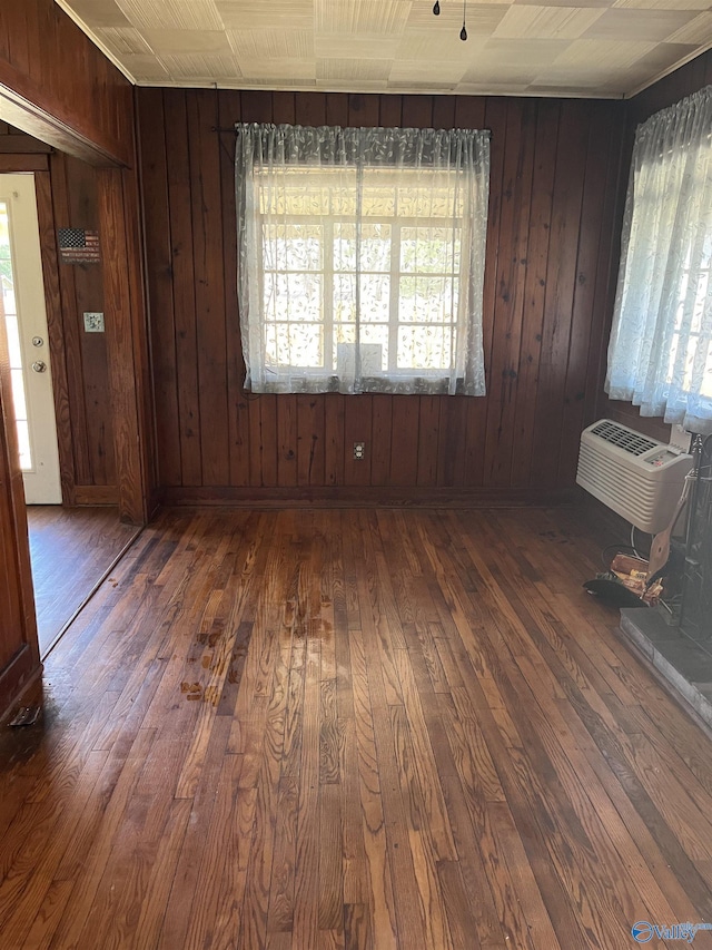 empty room featuring hardwood / wood-style flooring, wooden walls, and a wall mounted air conditioner