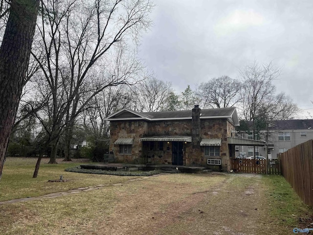 view of front of house with a front lawn, fence, stone siding, and a chimney