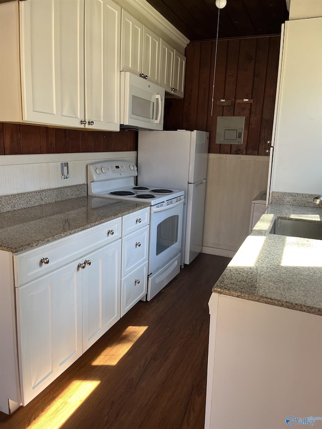 kitchen with a sink, light stone counters, dark wood finished floors, white cabinetry, and white appliances