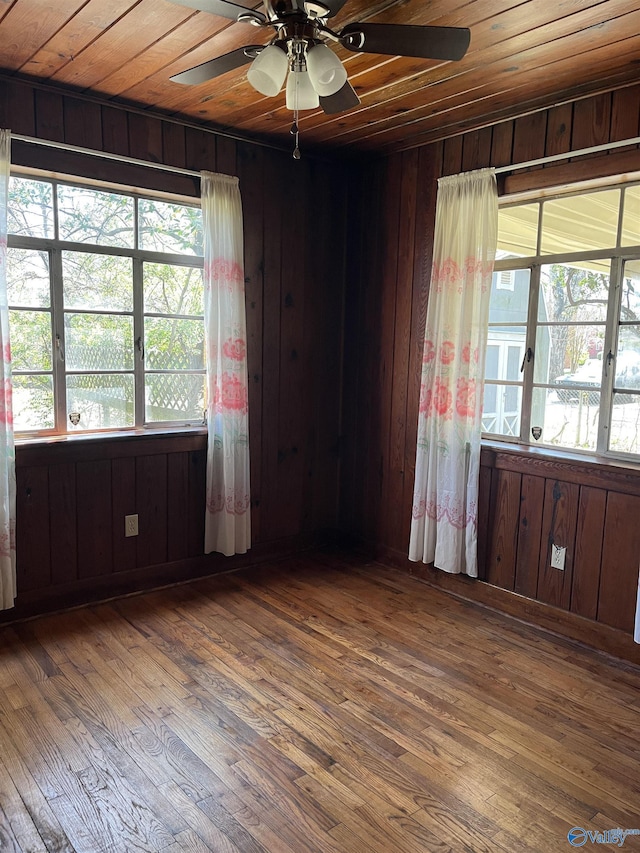 spare room with wood walls, wooden ceiling, a ceiling fan, and hardwood / wood-style flooring