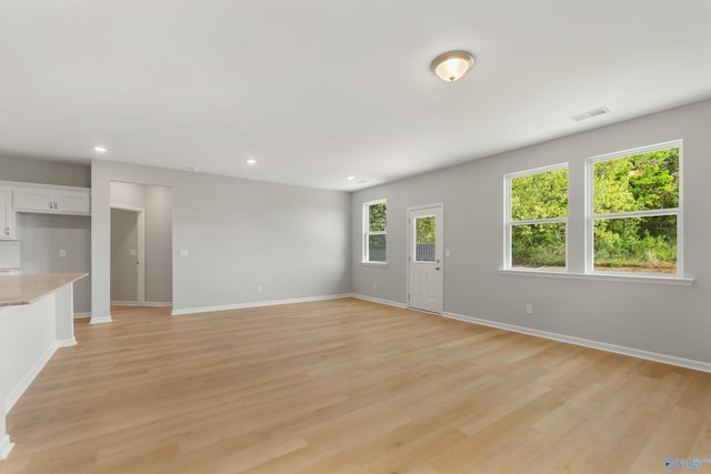 unfurnished living room with recessed lighting, visible vents, light wood-style flooring, and baseboards