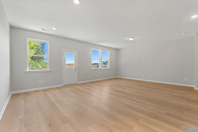 interior space featuring visible vents, baseboards, light wood-style floors, and plenty of natural light