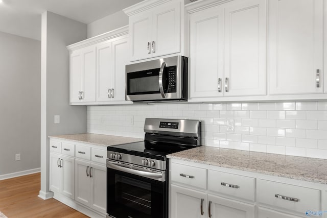 kitchen with appliances with stainless steel finishes, light wood-type flooring, decorative backsplash, and white cabinets