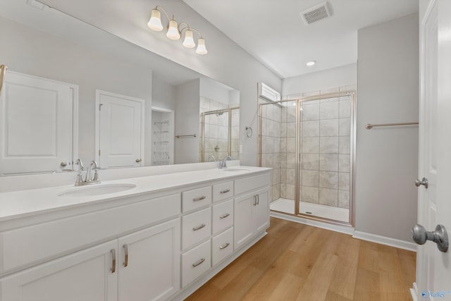 bathroom featuring visible vents, a shower stall, double vanity, and a sink