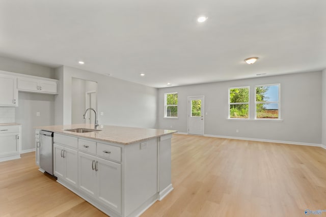 kitchen with dishwasher, a sink, open floor plan, and light wood-type flooring