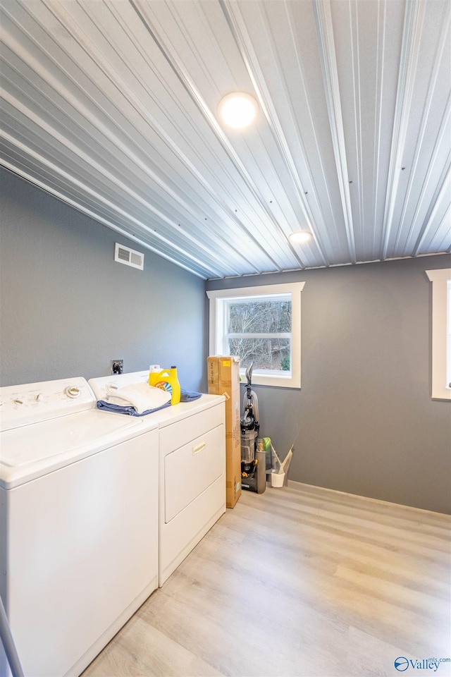 washroom with light hardwood / wood-style flooring and washer and dryer