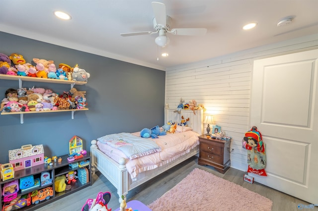 bedroom with ceiling fan, dark hardwood / wood-style flooring, and wood walls