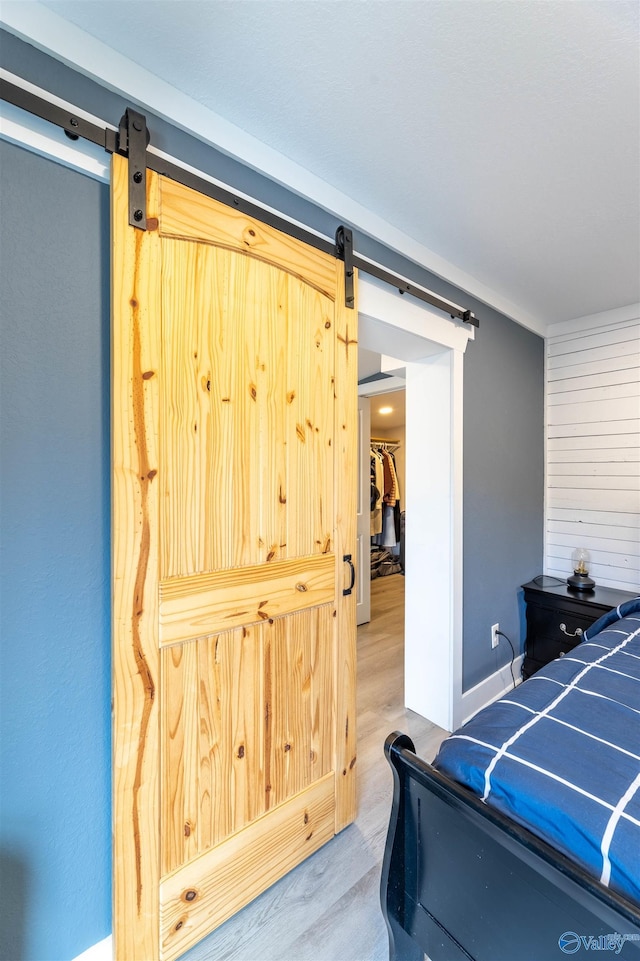 bedroom with wood-type flooring and a barn door