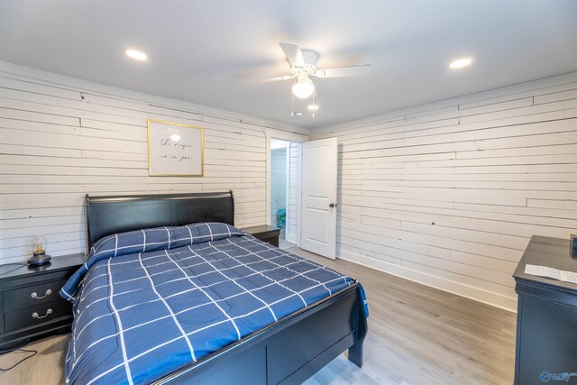bedroom featuring hardwood / wood-style flooring, wooden walls, and ceiling fan