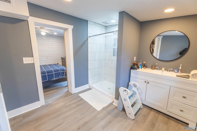 bathroom featuring ceiling fan, wood-type flooring, vanity, and a tile shower
