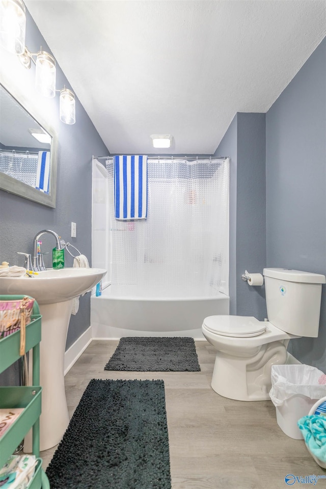 bathroom with hardwood / wood-style flooring, shower / tub combo with curtain, and toilet