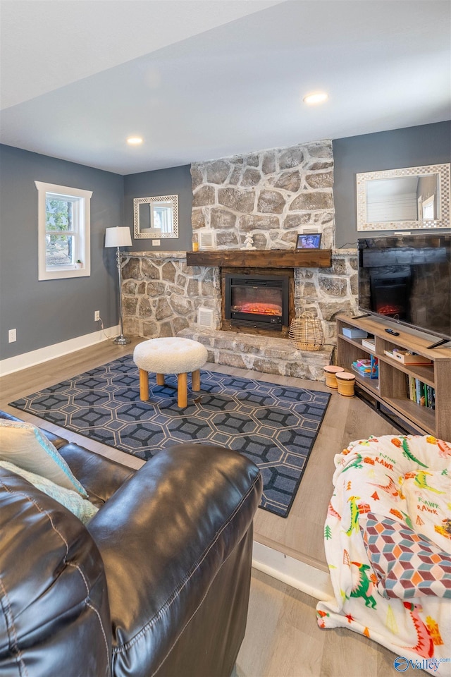living room with a stone fireplace and light hardwood / wood-style floors
