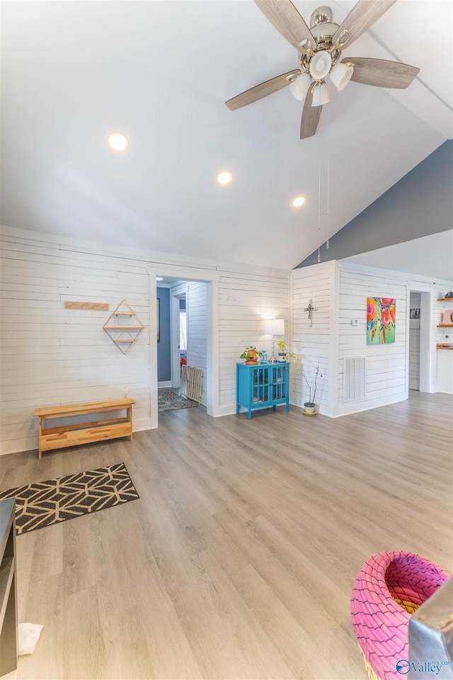 interior space featuring hardwood / wood-style flooring, vaulted ceiling, ceiling fan, and wood walls