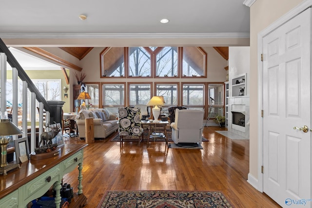 living room with crown molding, wood-type flooring, a tile fireplace, and a wealth of natural light