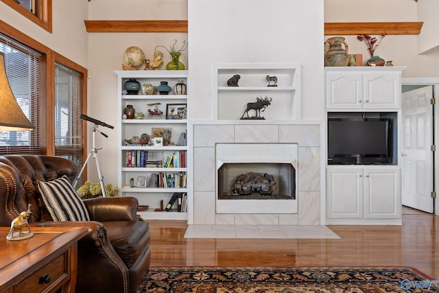 living room featuring built in shelves, dark hardwood / wood-style floors, and a tiled fireplace