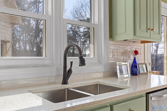 interior details featuring light stone counters, green cabinetry, sink, and tasteful backsplash