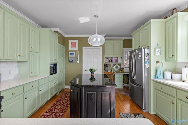 kitchen with stainless steel refrigerator, a center island, tasteful backsplash, wood-type flooring, and decorative light fixtures