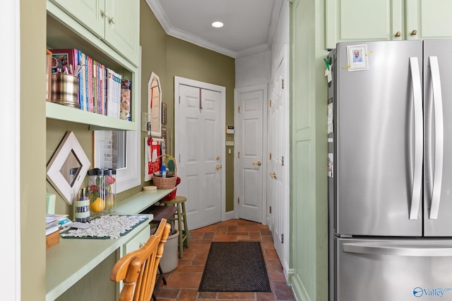 kitchen with stainless steel refrigerator, crown molding, built in desk, and green cabinets