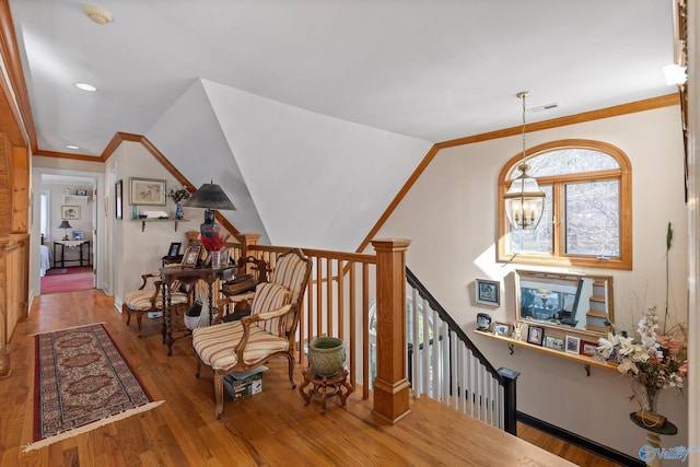 sitting room with wood-type flooring, ornamental molding, and an inviting chandelier