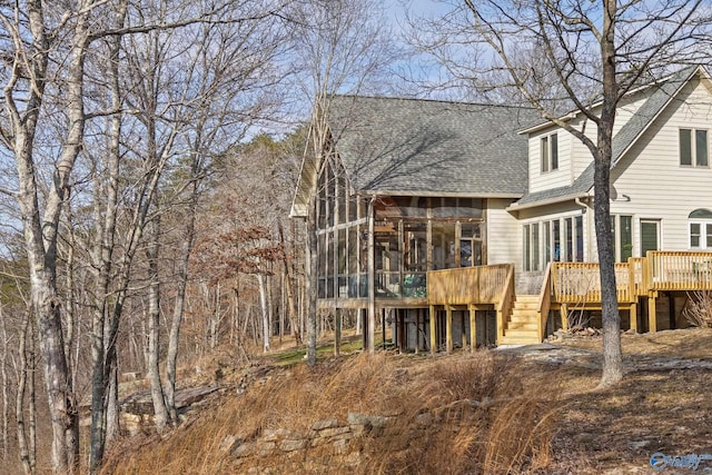 rear view of house with a wooden deck and a sunroom