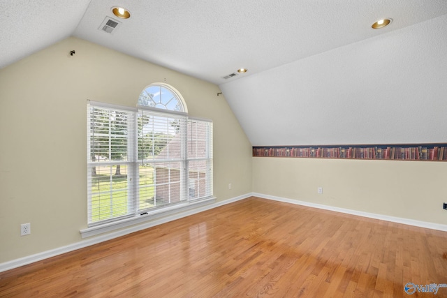 bonus room featuring vaulted ceiling, a textured ceiling, and light wood-type flooring