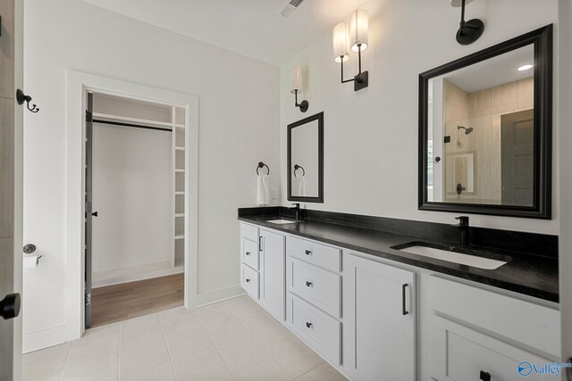 full bath with tile patterned floors, a stall shower, double vanity, a spacious closet, and baseboards
